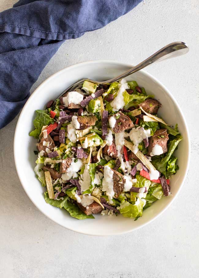 overhead photo of a bowl of steak taco salad drizzled with dressing