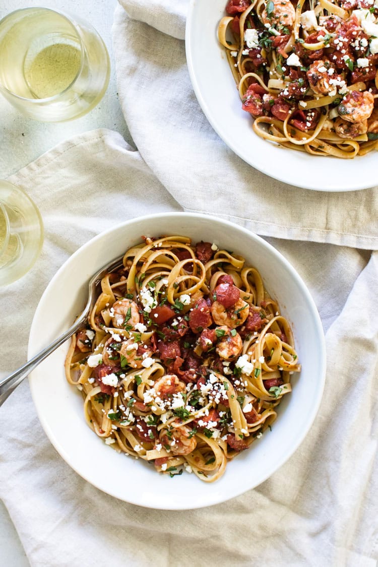 overhead photo of two bowls of shrimp fettuccine with glasses of white wine