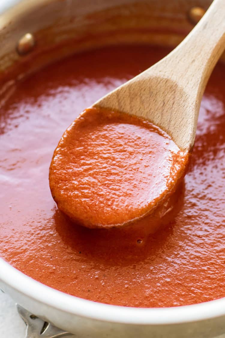 close-up up photo of a wooden spoon stirring enchilada sauce