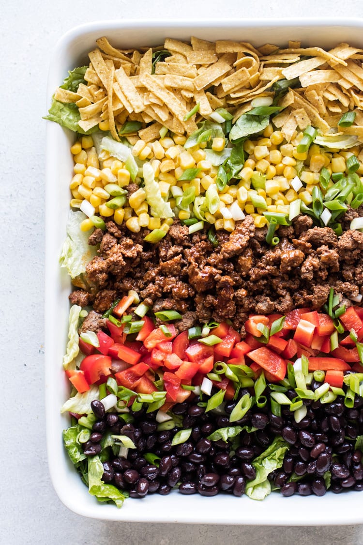 overhead photo of a taco salad with beans, peppers, corn, tortilla strips, ground beef and lettuce