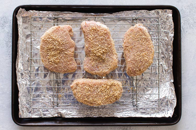 overhead photo of the breaded pork chops on a baking sheet