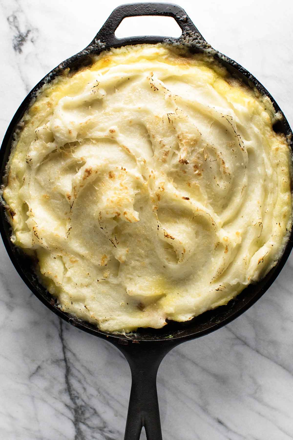 photo of mashed potatoes covering the filling in a skillet