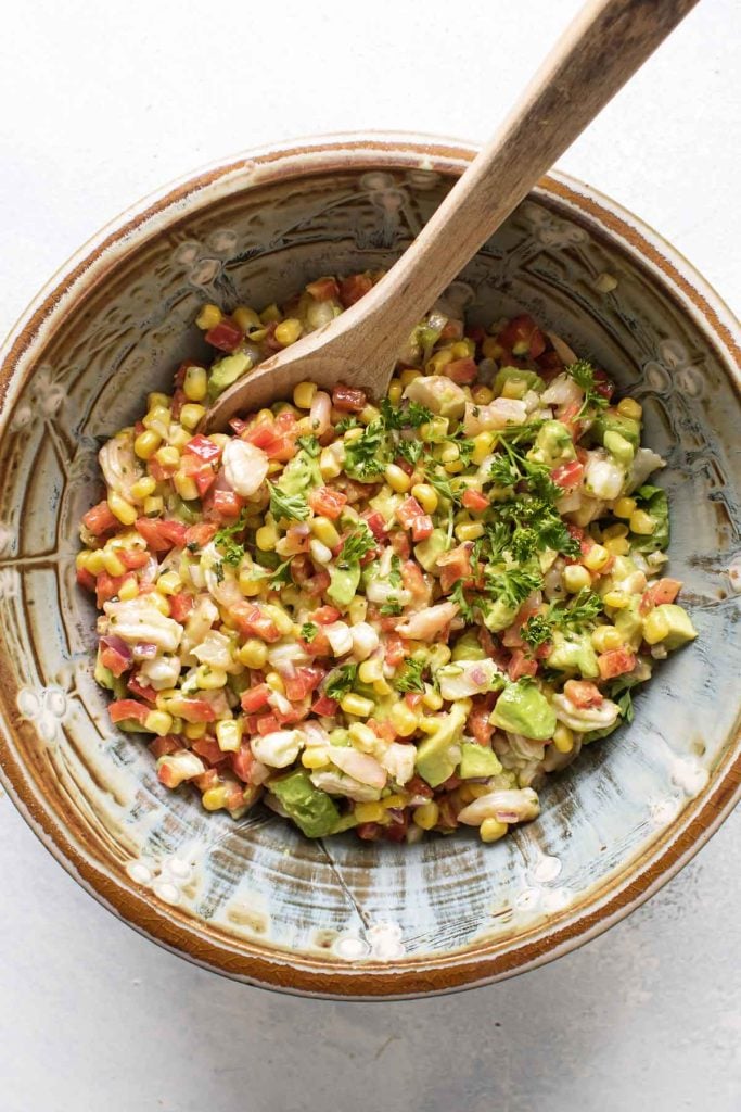 photo of a bowl of salad with a wooden spoon