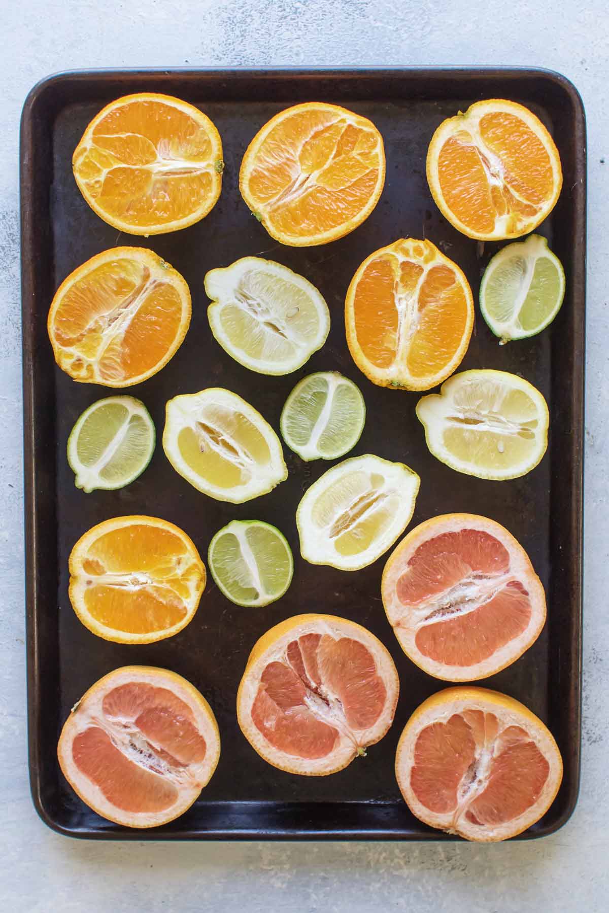 overhead photo of orange, lemon, lime, and grapefruit halves on a baking sheet