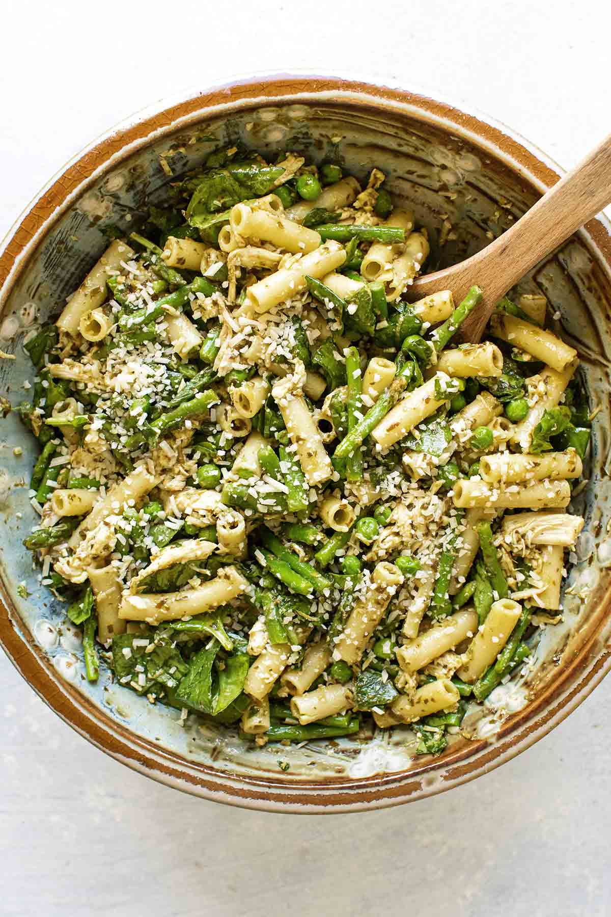 overhead photo of the pasta salad in a bowl with a wooden spoon