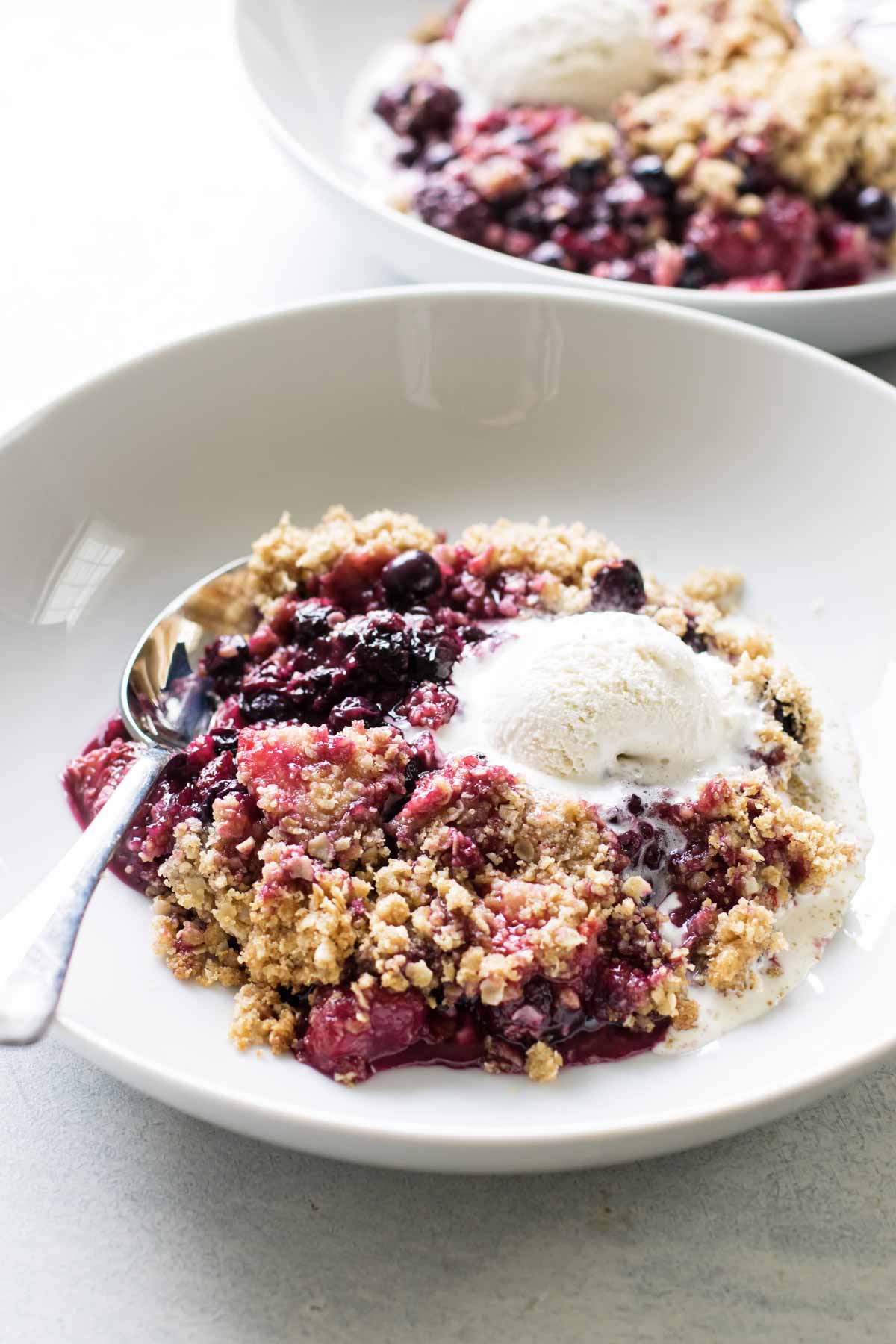 photo of a serving of berry crumble in a bowl with ice cream