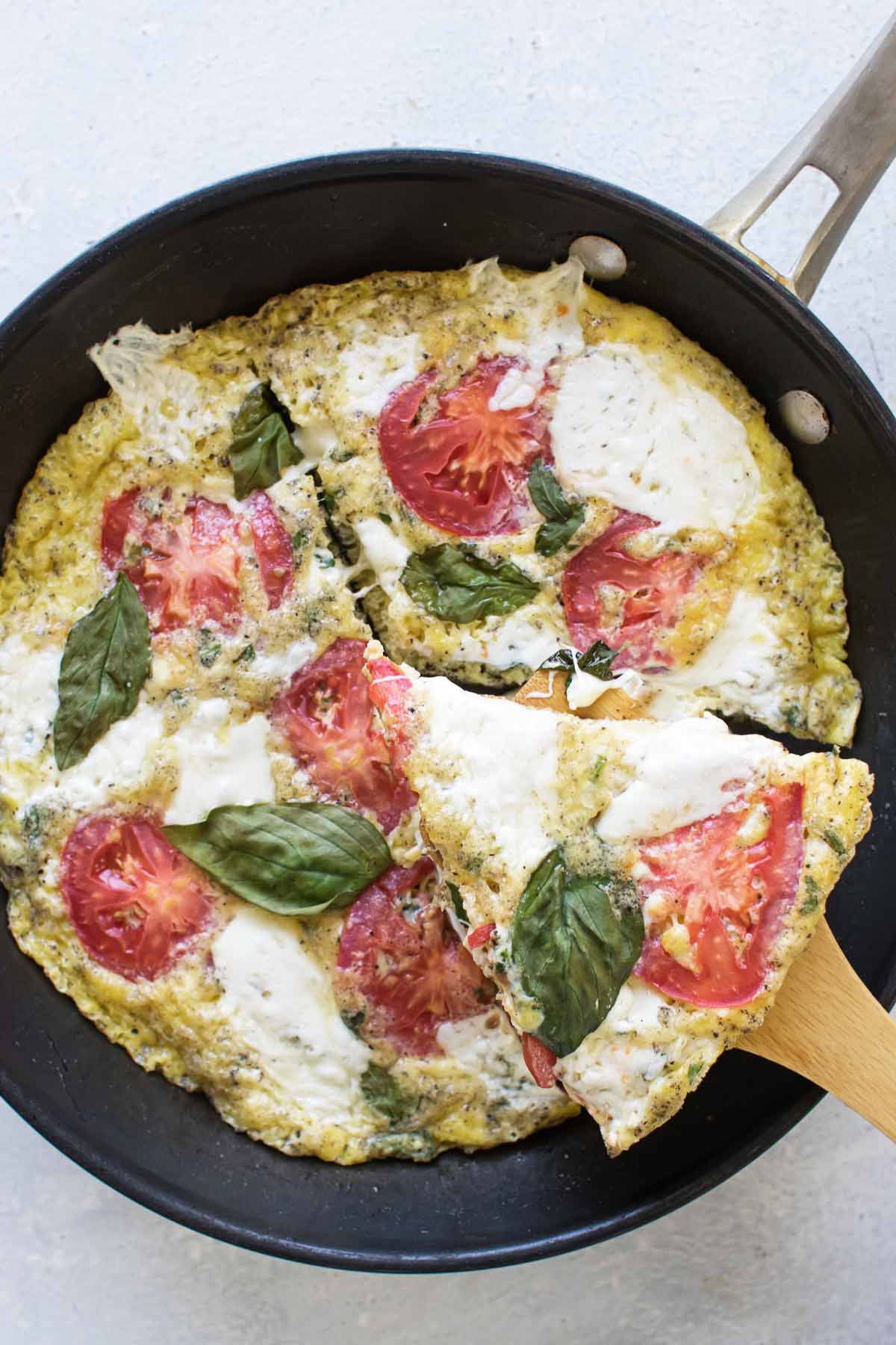 a slice of frittata being lifted out of a skillet.