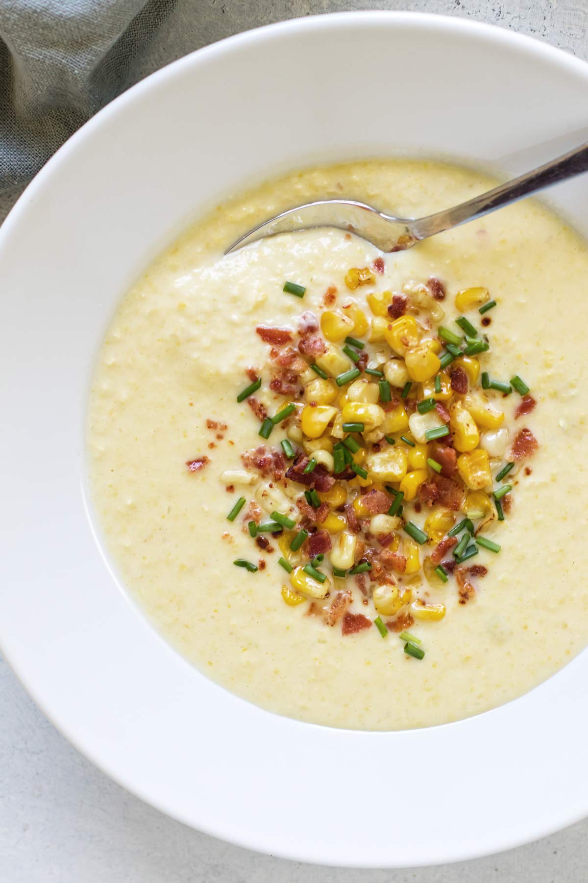 overhead photo of a bowl of corn soup with a spoon