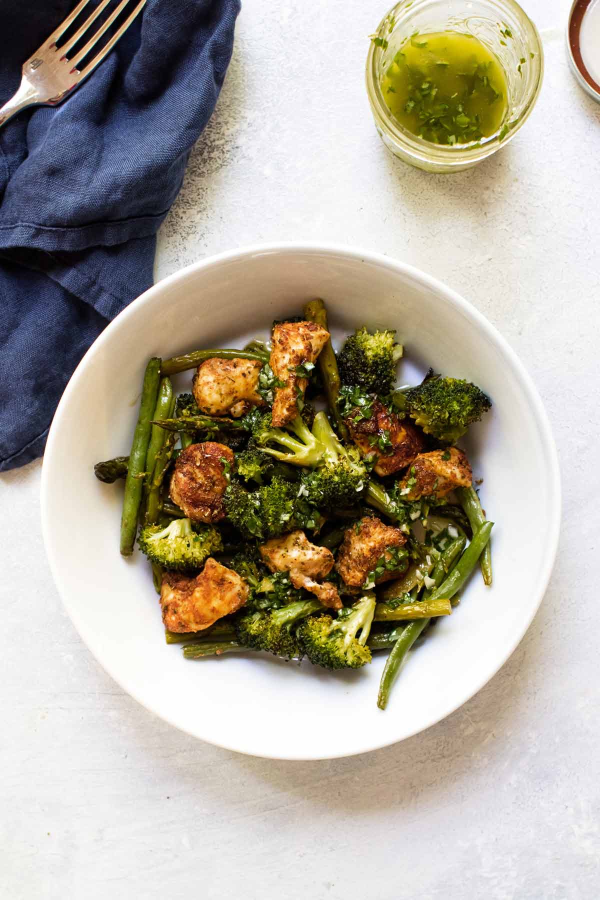 a bowl of chicken and veggies with dressing on the side.