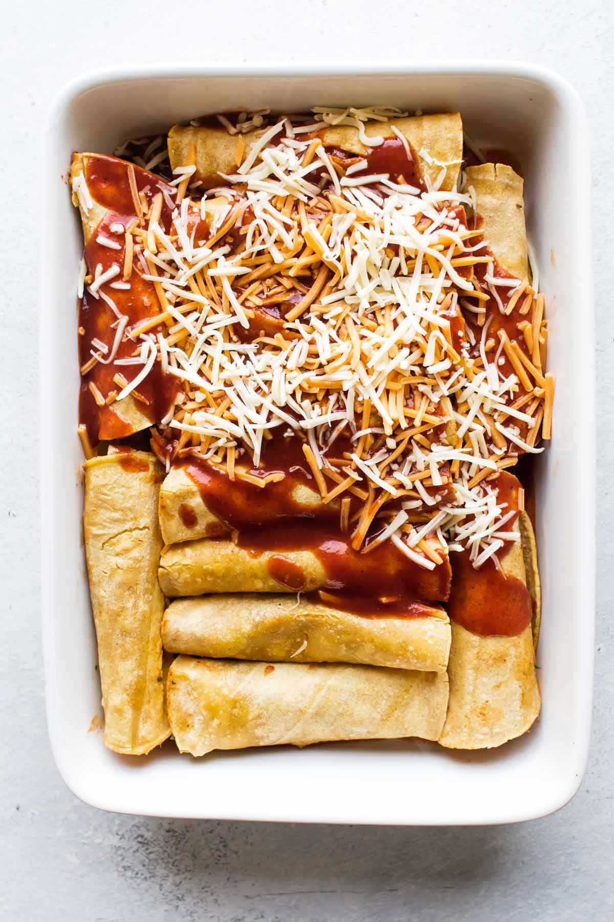 enchiladas being assembled in a baking dish.