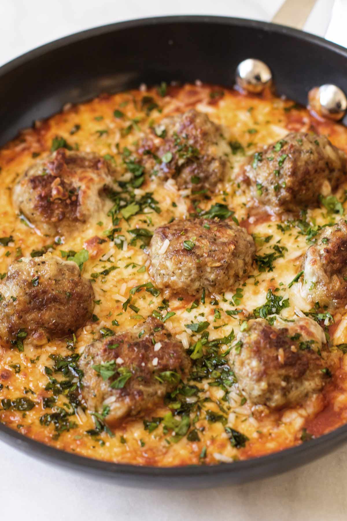 meatballs in a skillet with cheese and tomato sauce