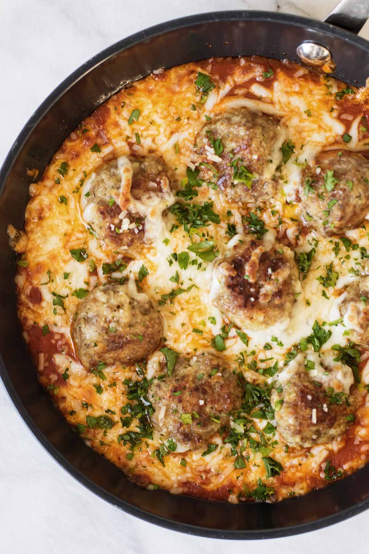 overhead shot of meatballs in a skillet with cheese and sauce