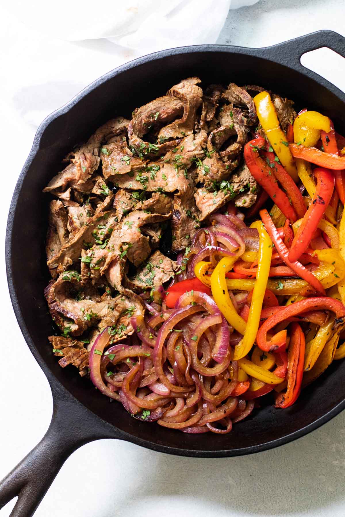 a cast iron skillet with beef, peppers, and onions