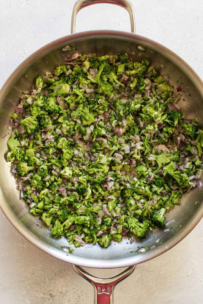 overhead shot of the broccoli and onions cooking in a skillet.