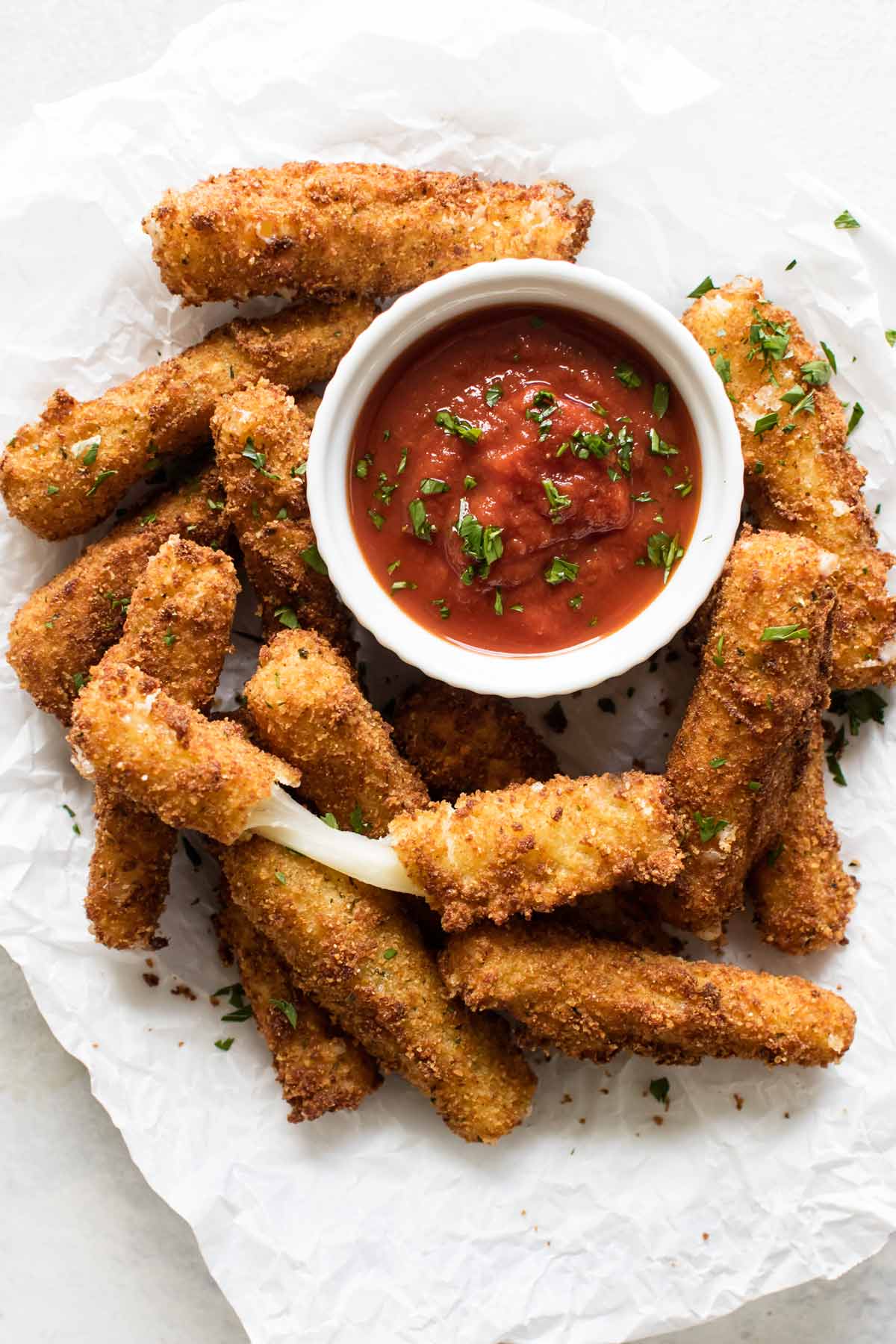 overhead shot of a plate of mozzarella sticks with marinara sauce.