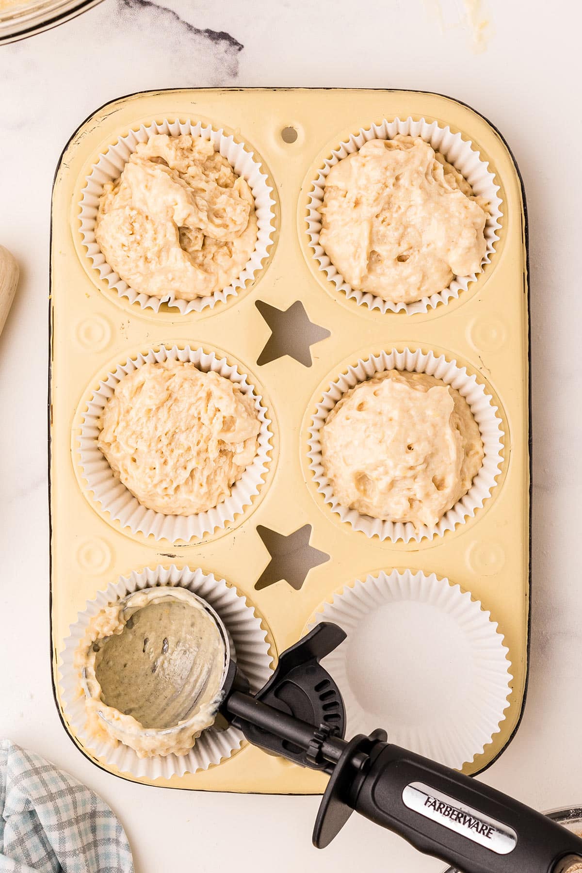 batter being scooped into a muffin pan.