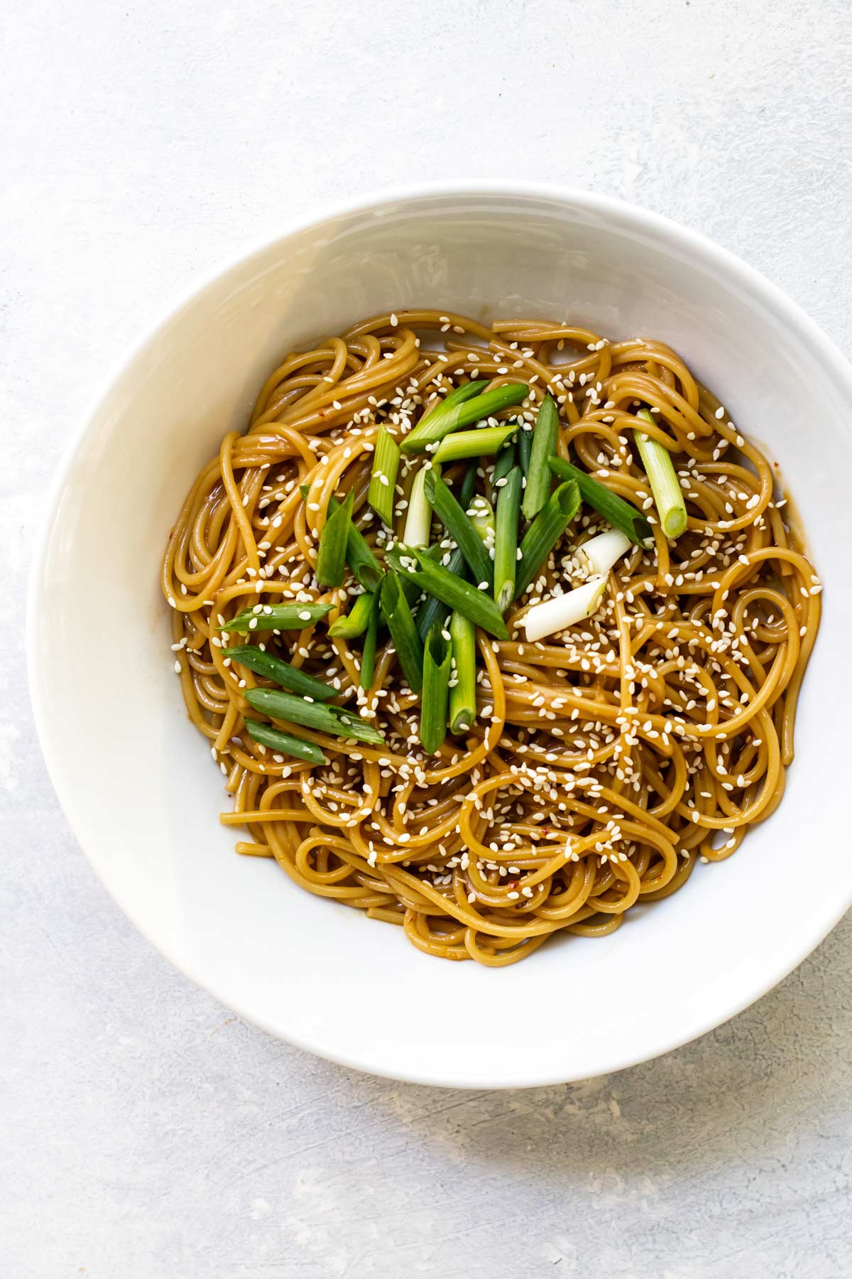overhead bowl of sesame noodles with green onions.