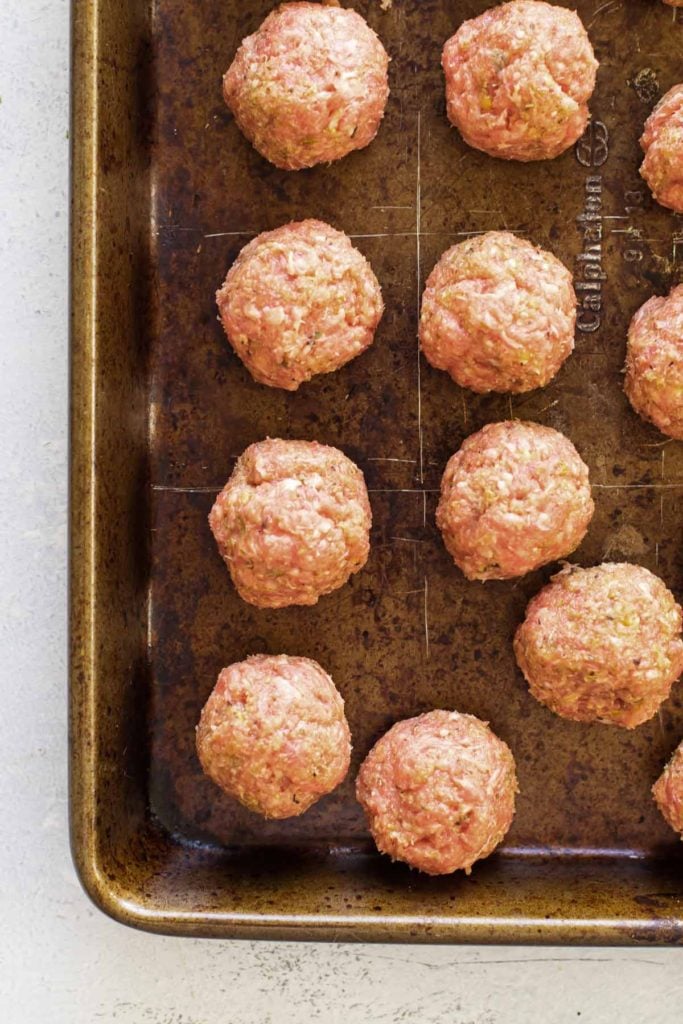 raw meatballs on a baking sheet.