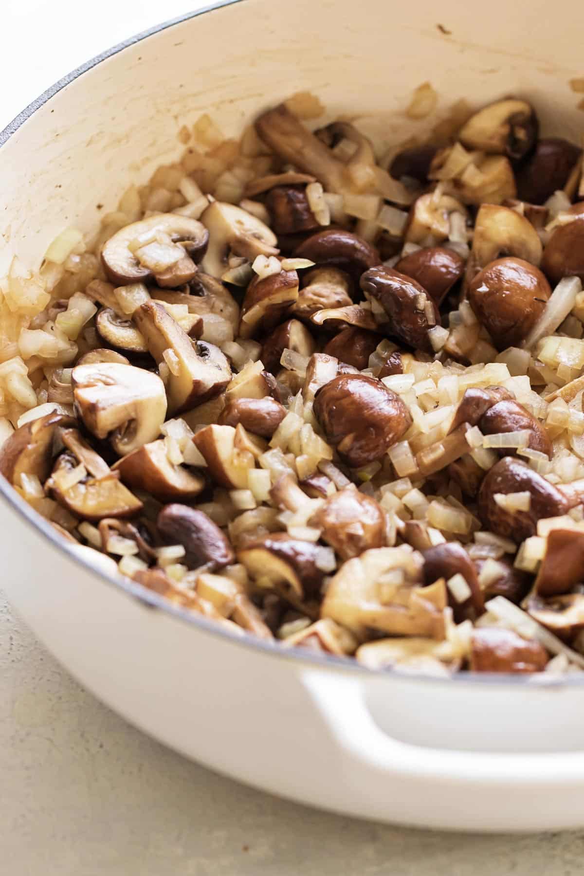 mushrooms and onions cooking in a pan.