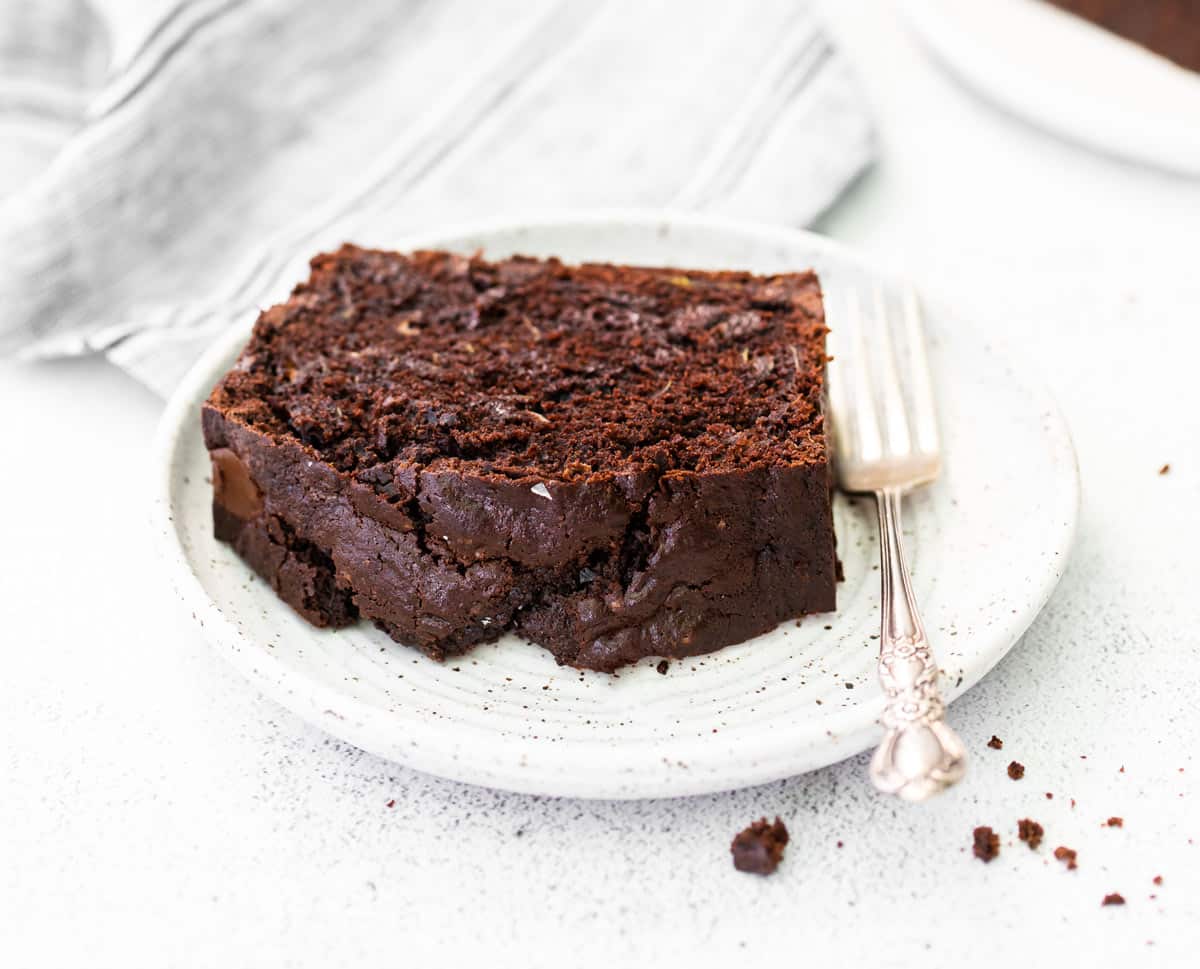 a slice of chocolate zucchini bread on a plate with a fork.