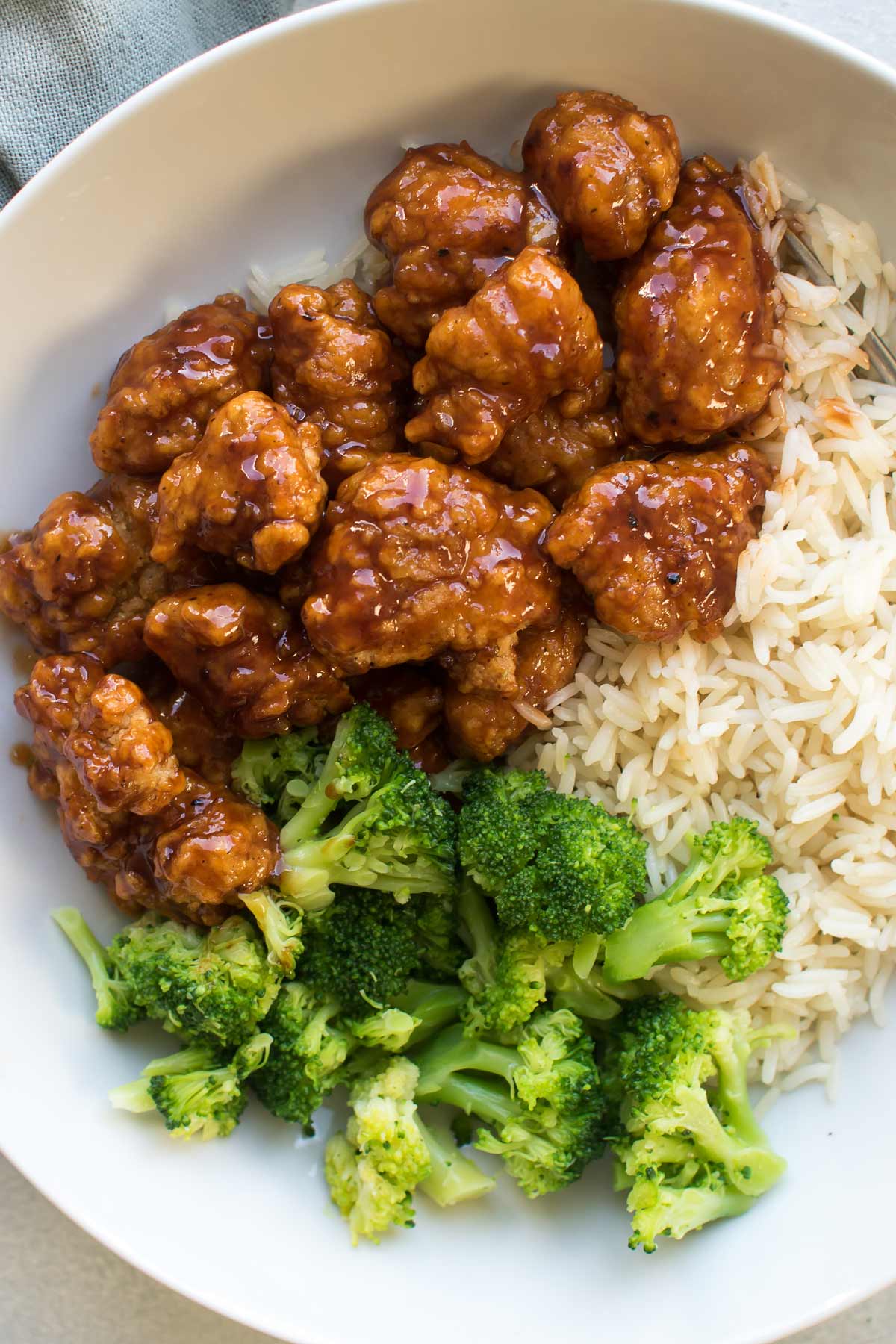 orange chicken in a bowl with rice and vegetables.