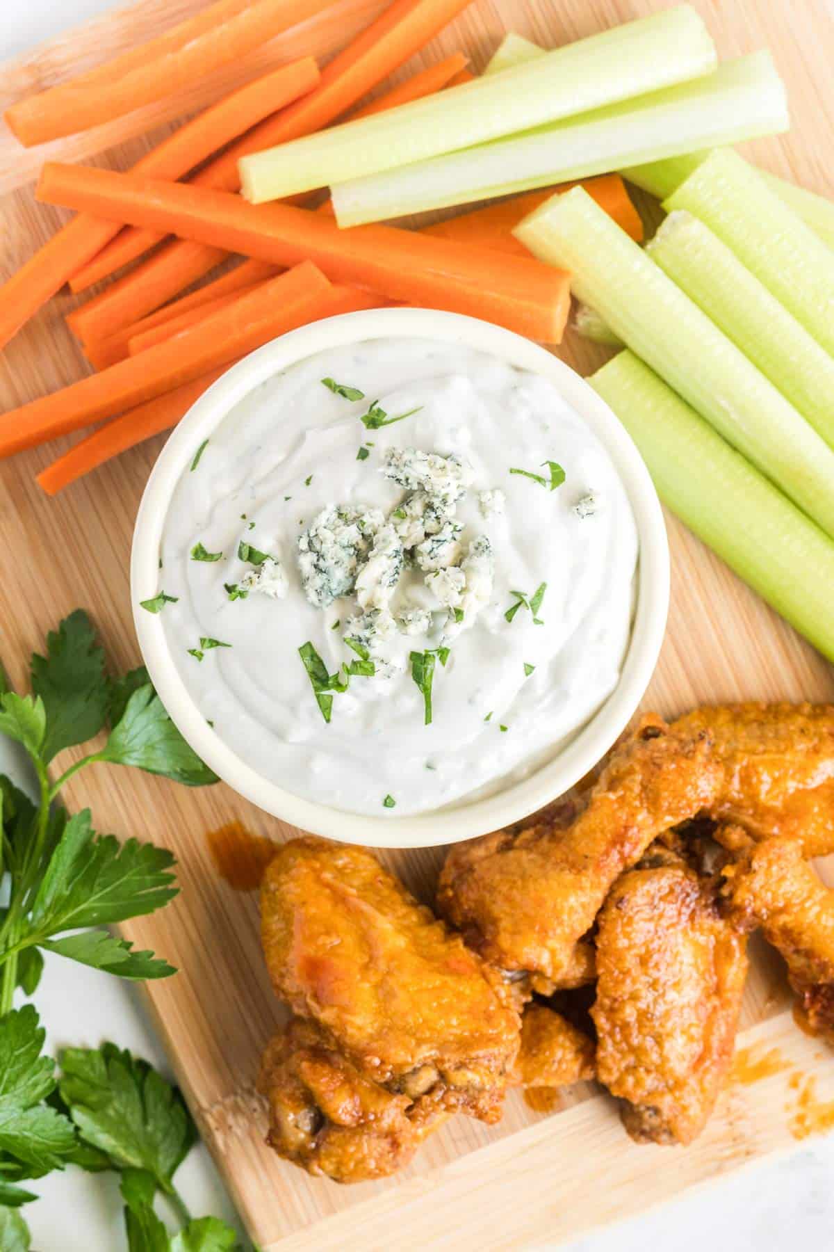 overhead shot of the dip in a bowl with veggie sticks and chicken wings.