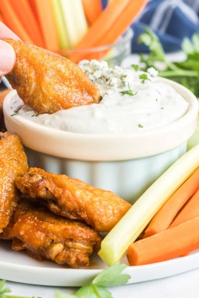 a buffalo chicken wing being dipped in the dip.