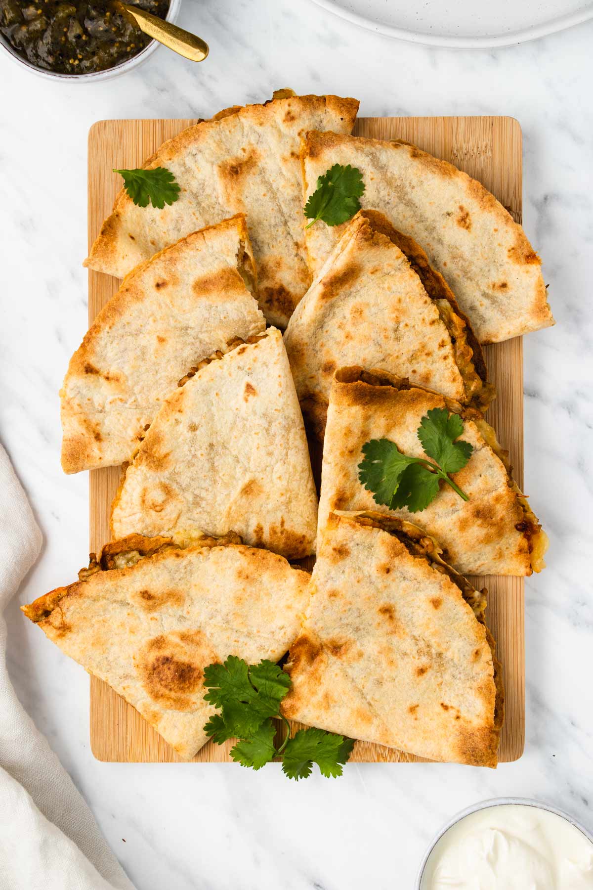 quesadillas on a board garnished with cilantro.