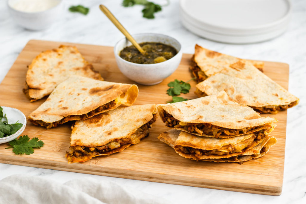 quesadillas on a cutting board with a bowl of salsa.