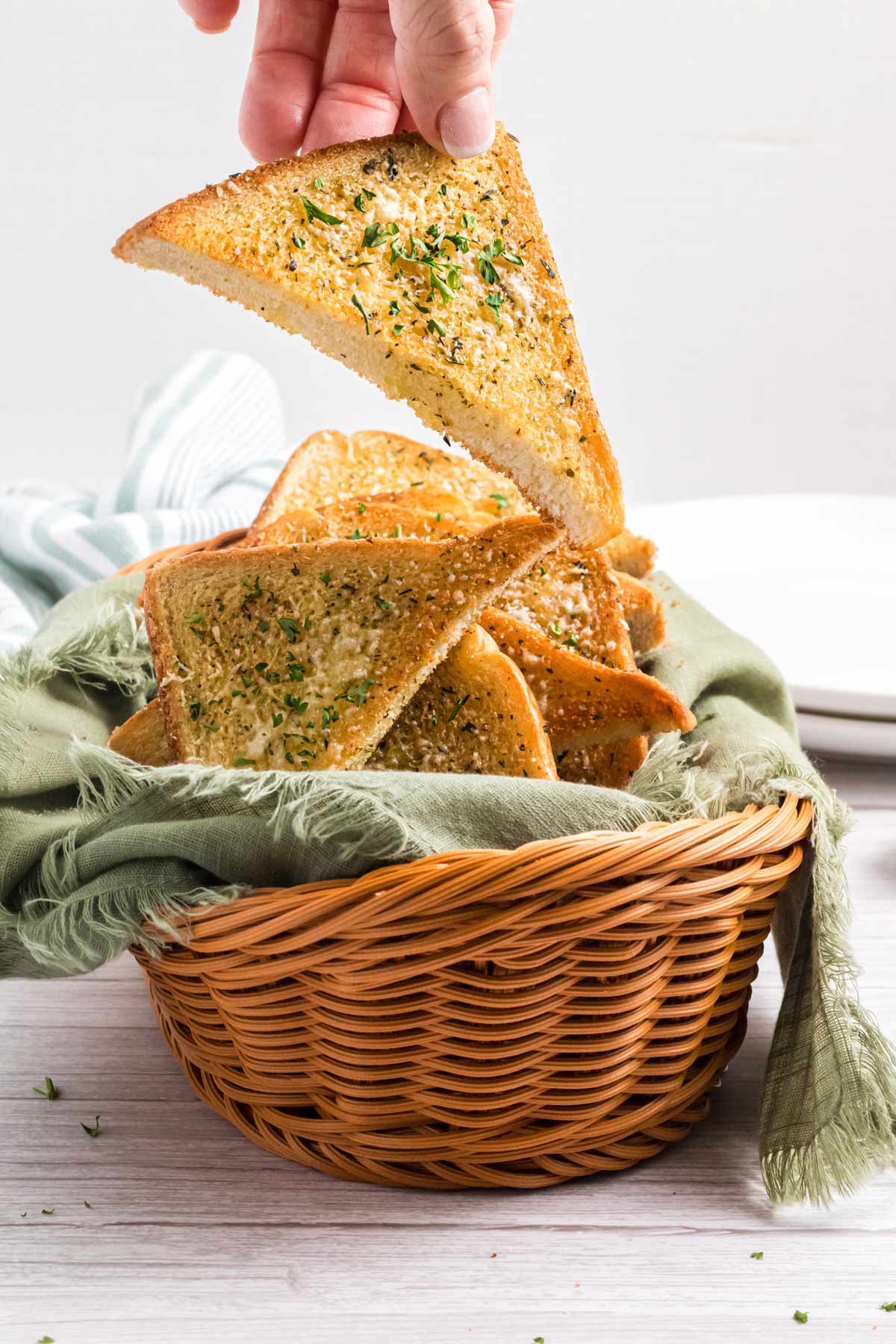 a piece of garlic toast being lifted out of a bread basket.