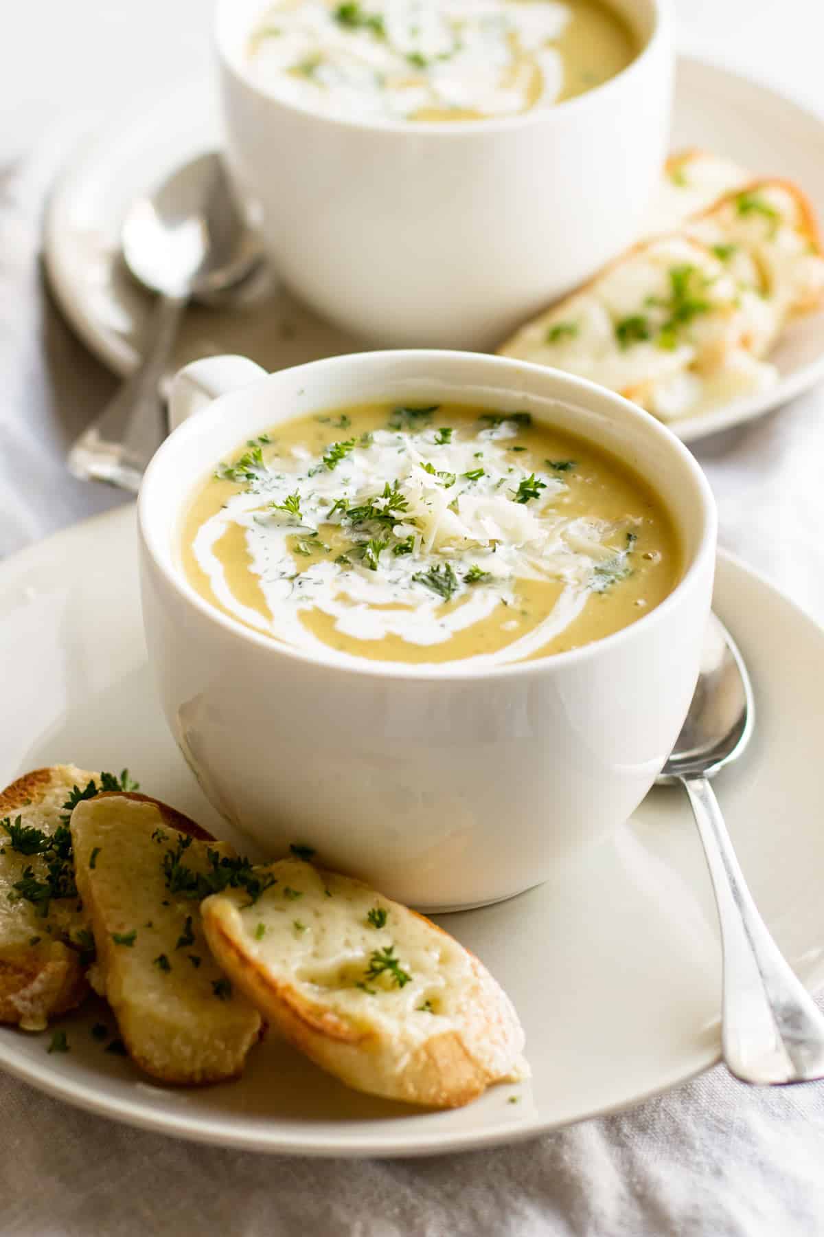 a bowl of squash soup on a plate with toasted baguette.
