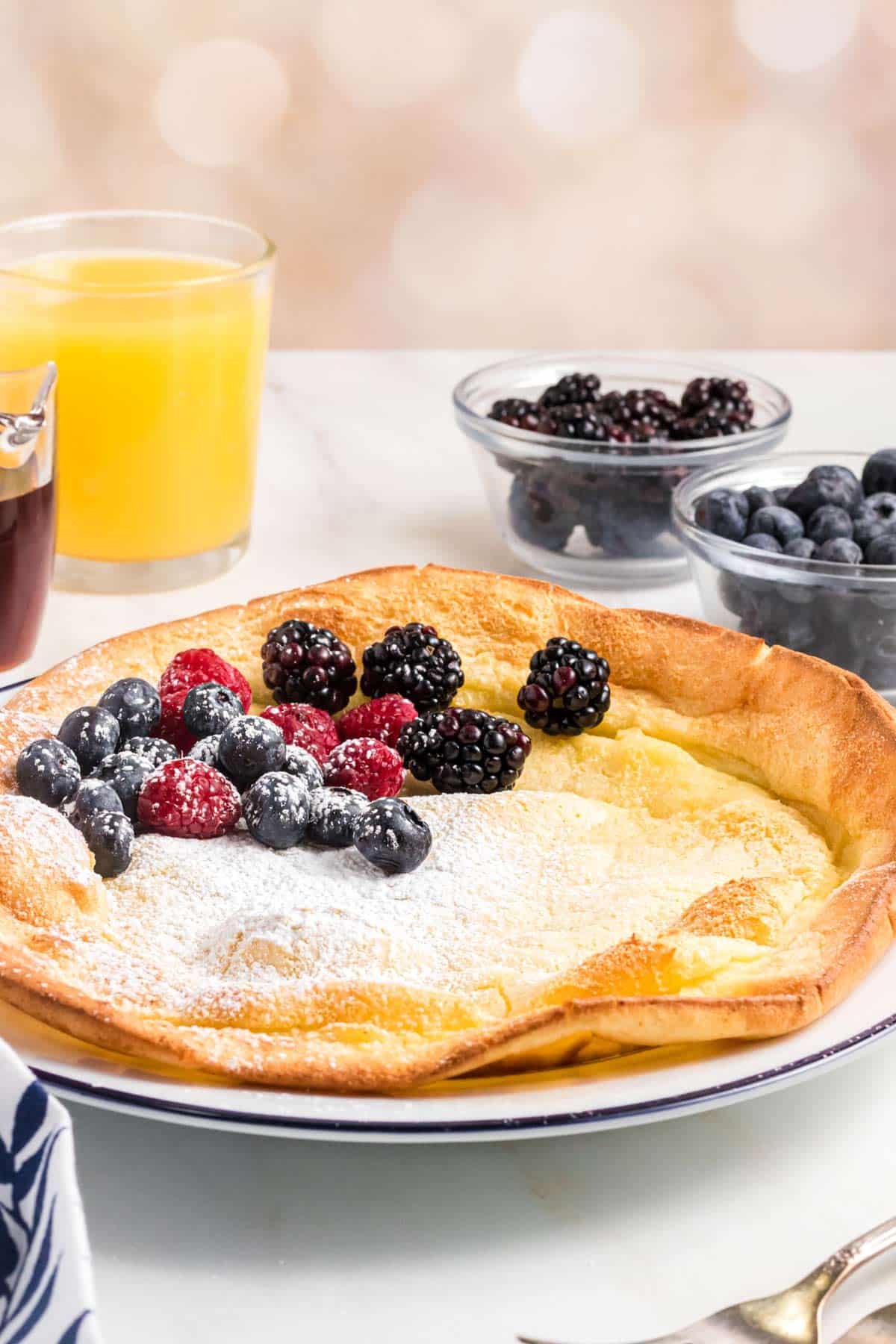 a dutch baby on a plate topped with berries and powdered.