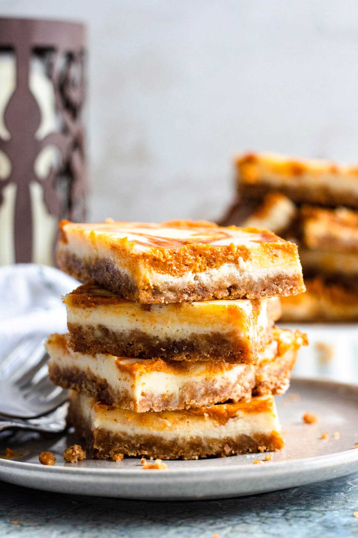 a stack of pumpkin cheesecake squares on a plate.