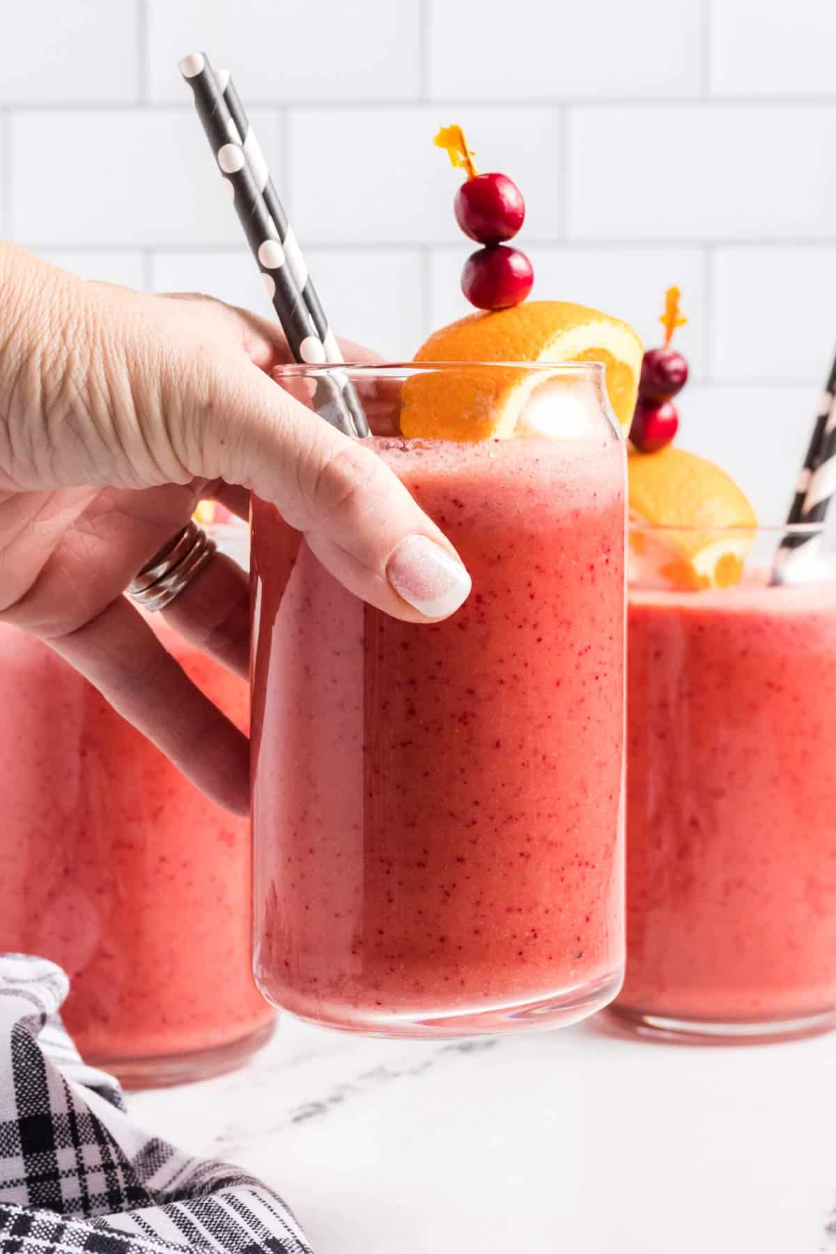 a hand lifting up a glass of smoothie.