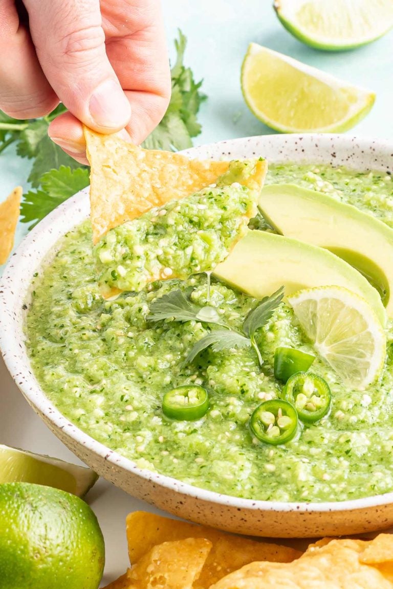 a bowl of avocado salsa verde with a chip being dipped.