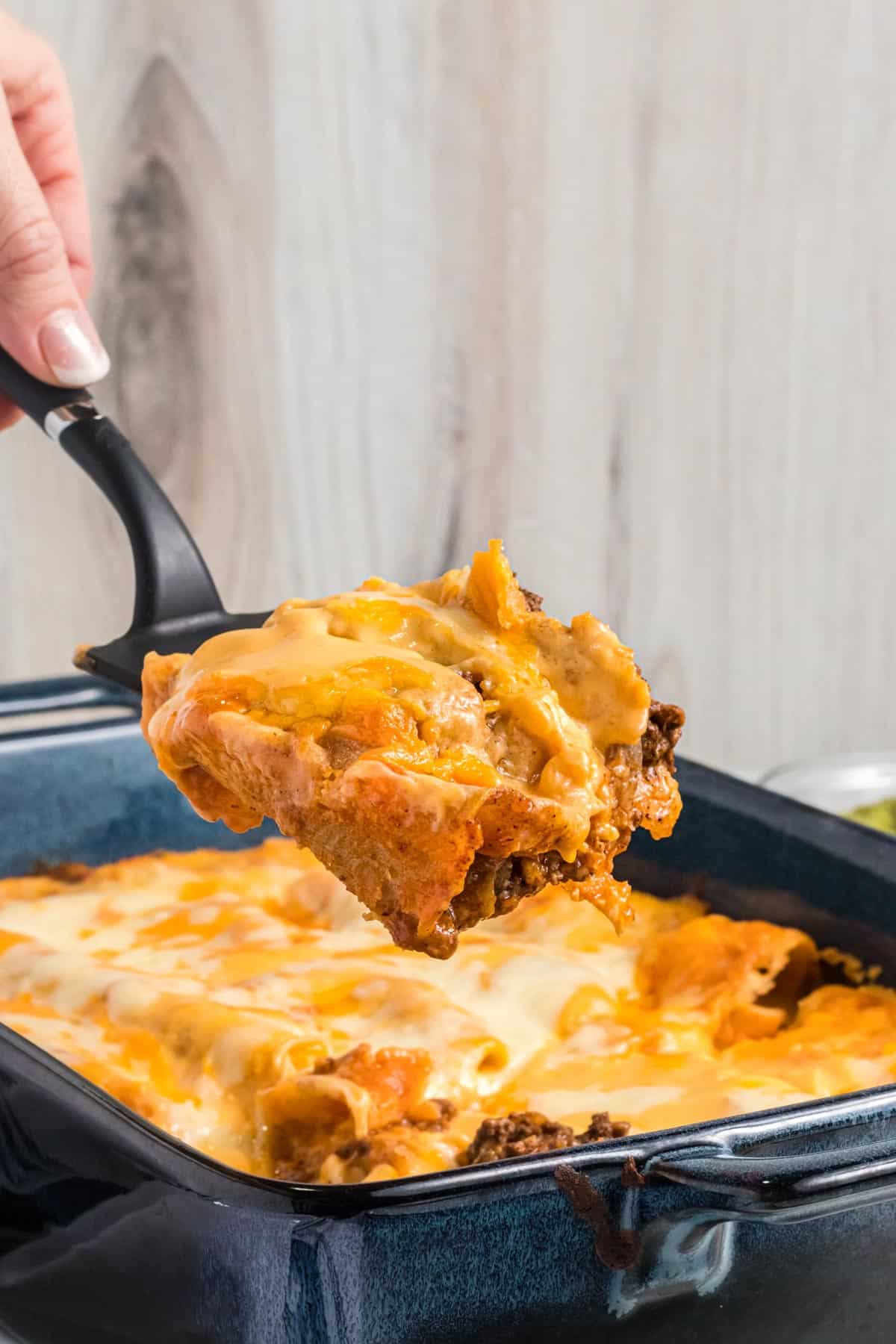 enchiladas being lifted out of a pan.