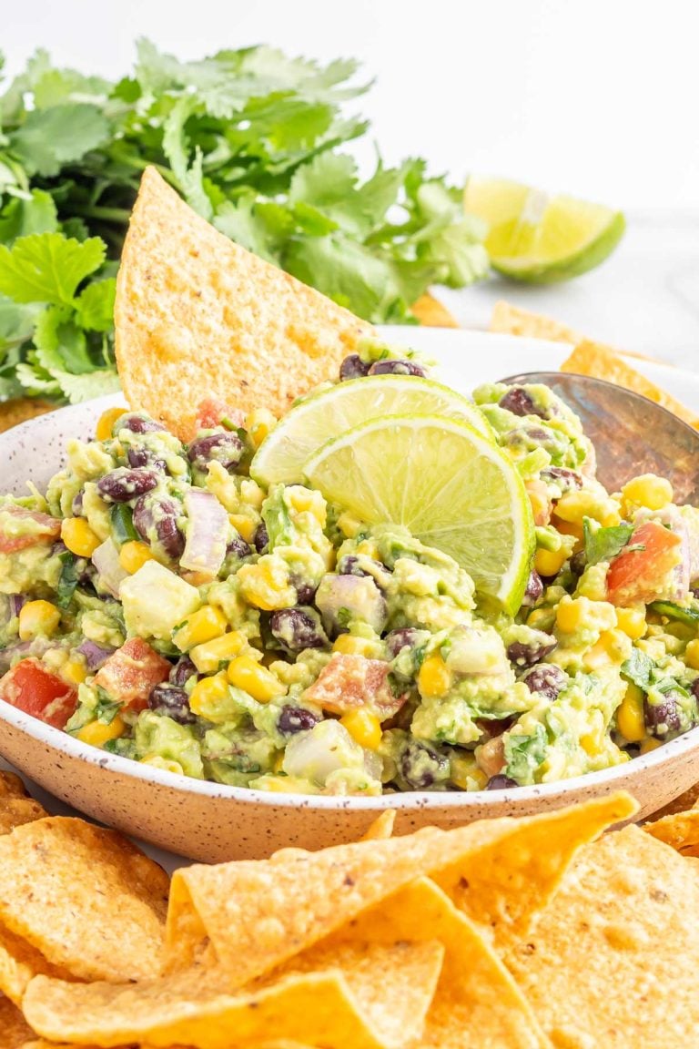 cowboy caviar guacamole in a bowl with tortilla chips around it.