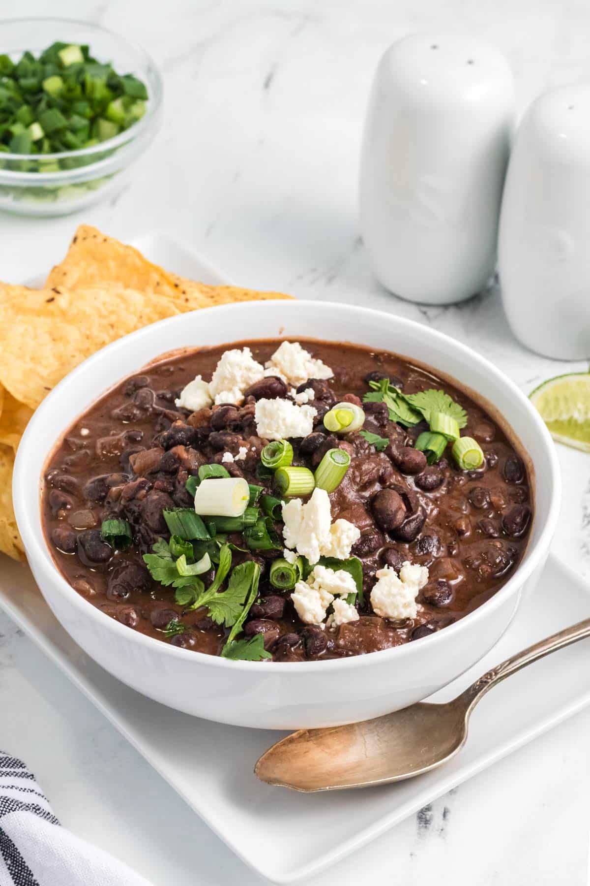 a bowl of black bean soup topped with garnishes.