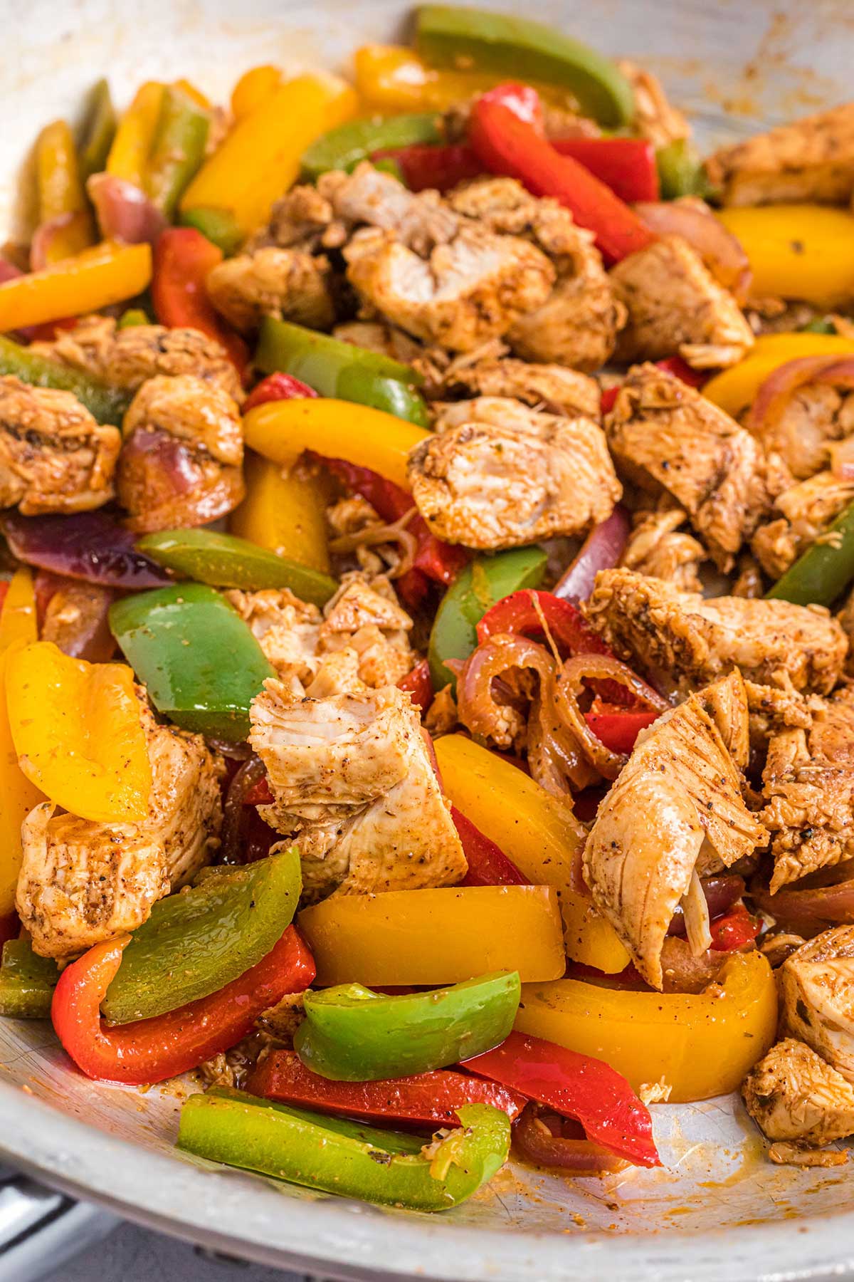 close-up shot of the chicken and peppers in a skillet.