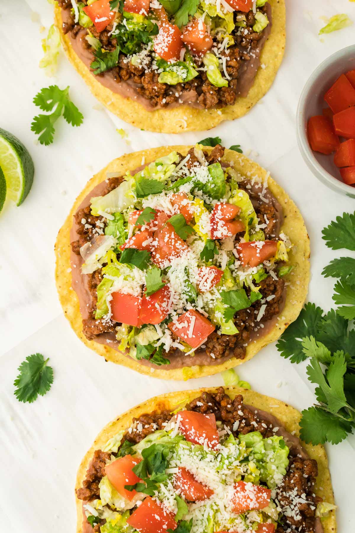 overhead shot of tostadas with beef cheese, lettuce and tomatoes.