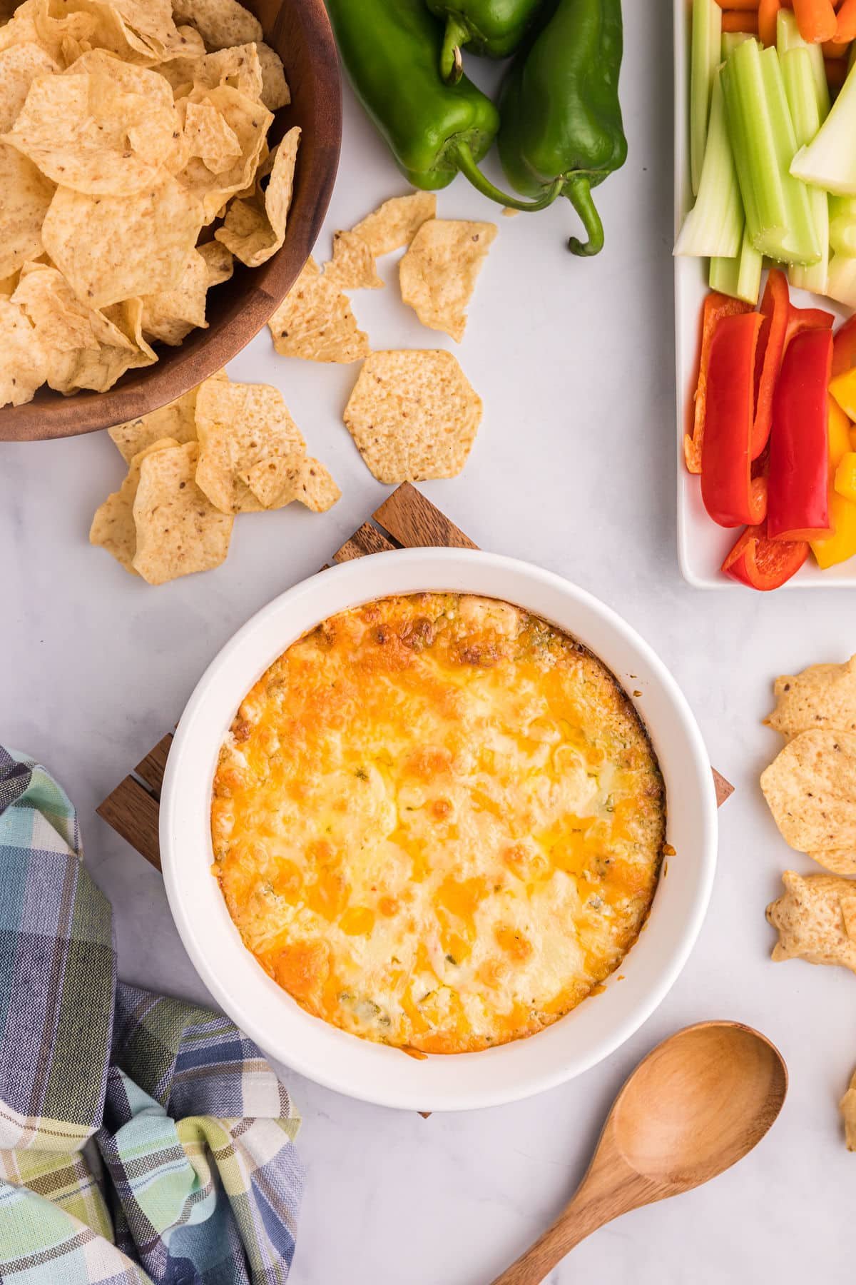 the baked dip with a bowl of chips and veggie sticks on the side.