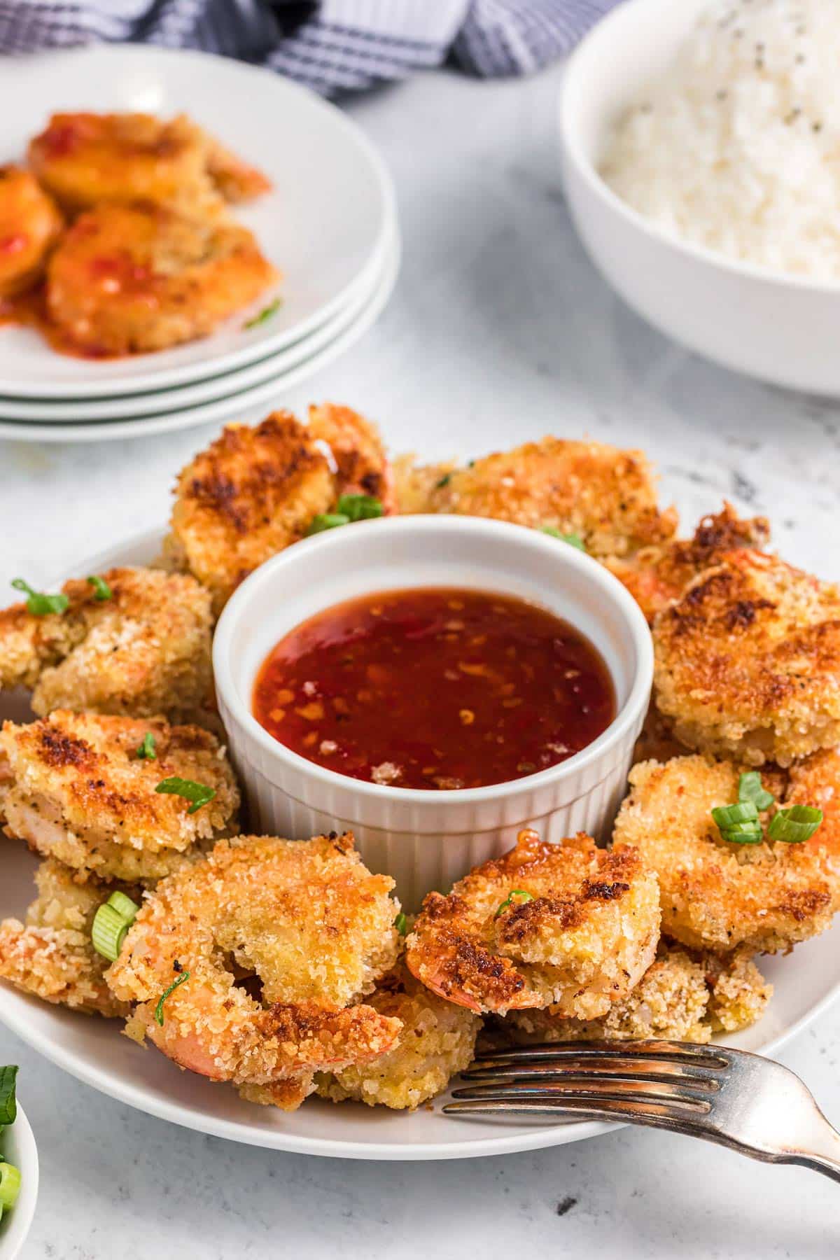 crispy panko shrimp on a serving plate with a bowl of sweet chili sauce.