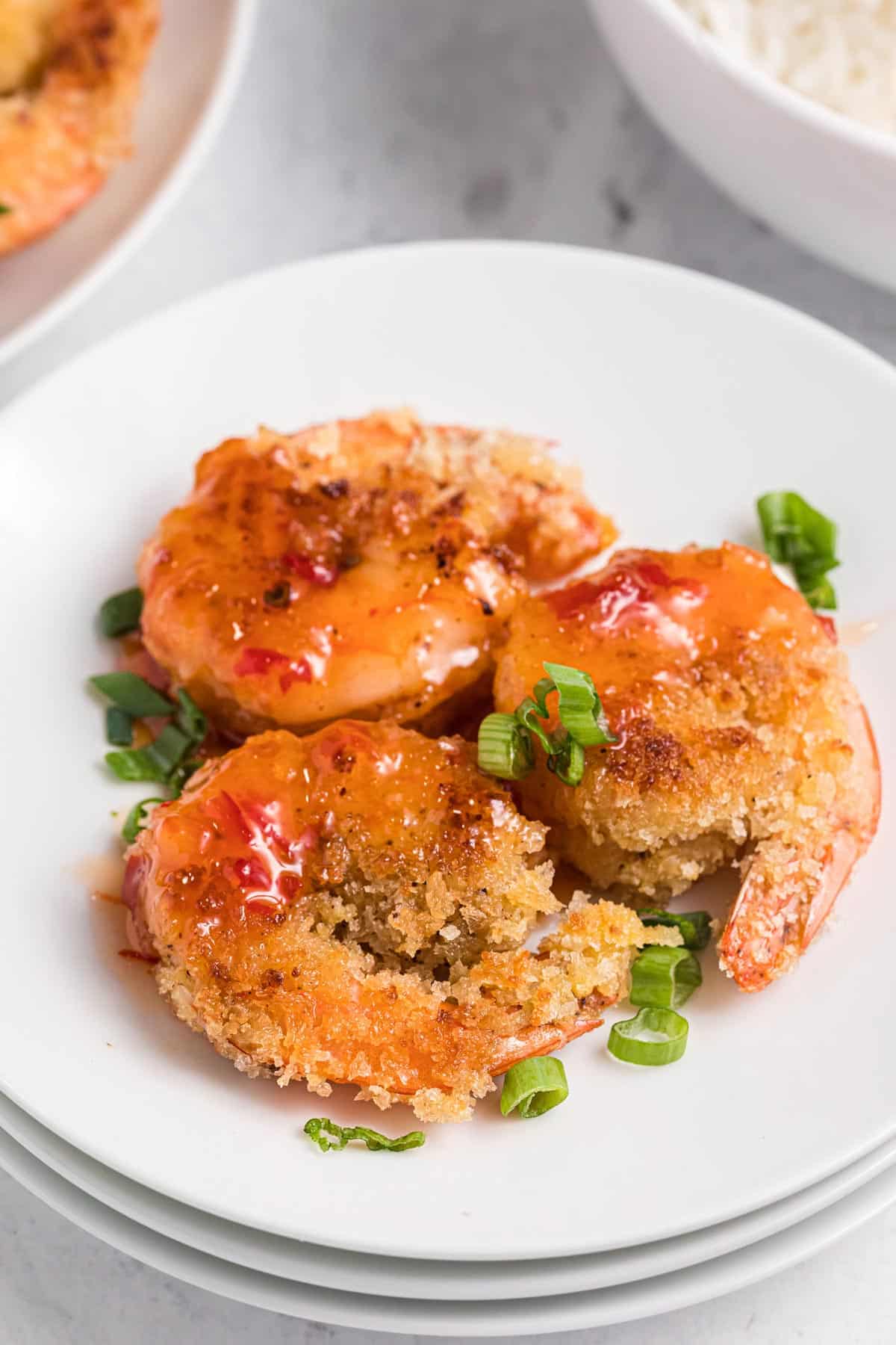 three shrimp on a plate with sauce drizzled over the top.