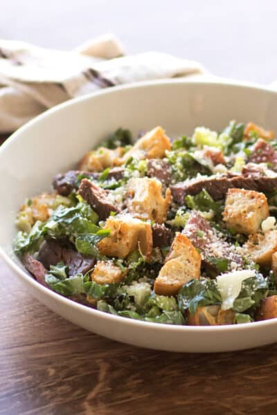 a caesar salad with steak and croutons.