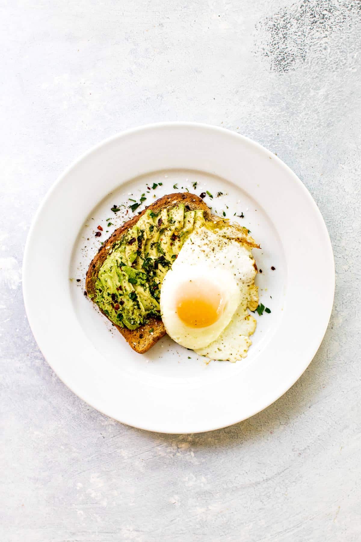 egg and avocado toast on a white plate.