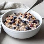 blueberry oatmeal in a bowl with a blue striped napkin next to it.
