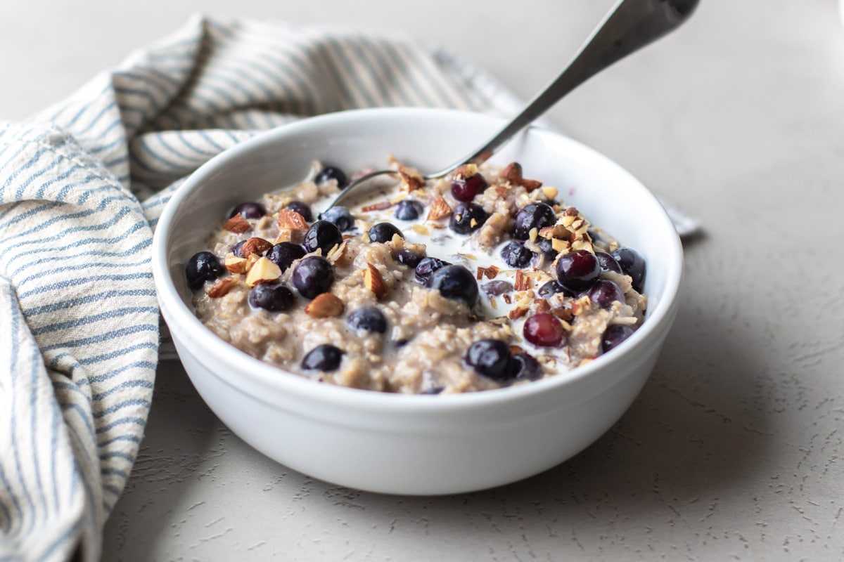 blueberry oatmeal in a bowl with a blue striped napkin next to it.
