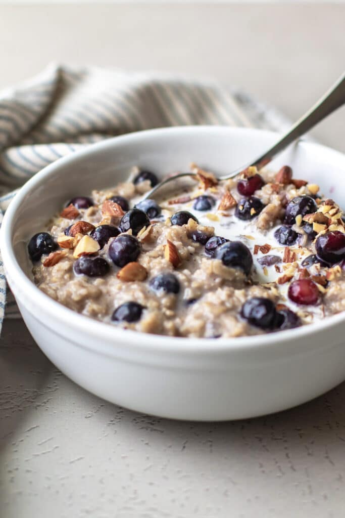 a bowl of oatmeal with blueberries, milk, and chopped almonds.