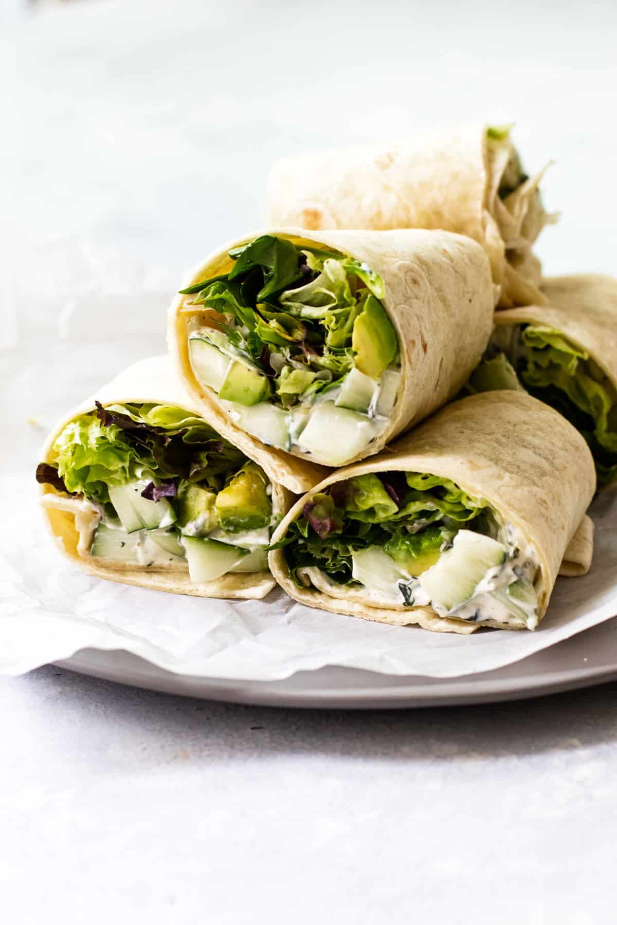 a stack of cucumber avocado wraps on a plate.