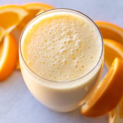 a smoothie with orange slices in the background.